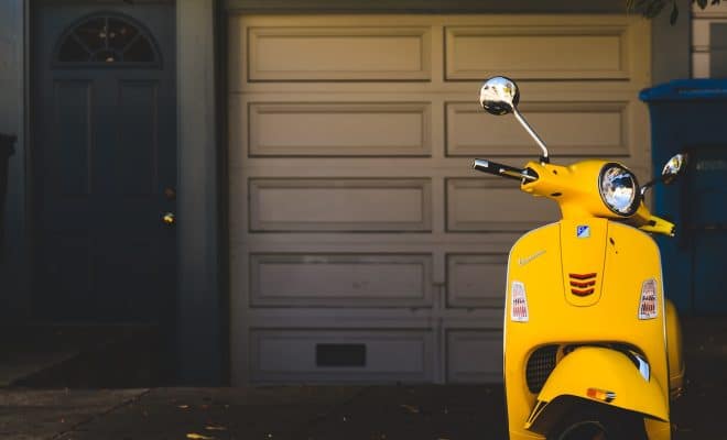 yellow motor scooter parked near white garage door