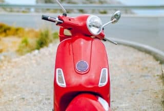 red Vespa motor scooter on side of the road